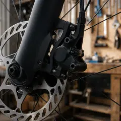 Gros plan sur un étrier de frein à disque de vélo, prêt pour le réglage. L'atelier de mécanique est visible en arrière-plan.