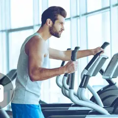 Un homme s'entraîne sur un vélo elliptique. Combien de temps faut-il pour voir des résultats ? L'icône d'une balance suggère la perte de poids.