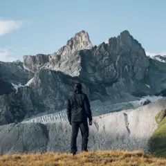 Un randonneur contemple les sommets majestueux du tour des glaciers de la Vanoise 3 jours. Paysage alpin grandiose.