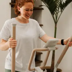 Femme souriante sur un vélo elliptique, suivant un programme vélo elliptique perdre graisse.