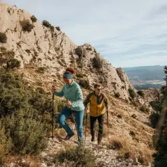 Deux randonneurs font du fast hiking sur un sentier rocailleux, profitant d'un paysage montagneux spectaculaire.
