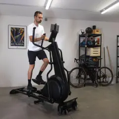 Homme s'entraînant sur un vélo elliptique pour la perte de poids dans un garage aménagé.