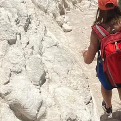 Randonneuse avec sac à dos rouge sur un sentier rocailleux, tout l'équipement nécessaire pour le GR20.
