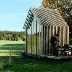 Deux randonneurs s'arrêtent près d'une cabane moderne, planifiant leur rando Jura 2 jours boucle.