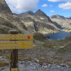 Panneau indicateur pour la randonnée vallée des Merveilles 2 jours. Lac d'altitude et montagnes escarpées.