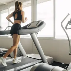 Une femme court sur un tapis de course, profitant d'une séance d'entraînement avec vue sur la mer.