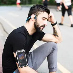 Un homme avec des écouteurs sans fil et un brassard pour téléphone, profitant de courir avec musique sans téléphone.