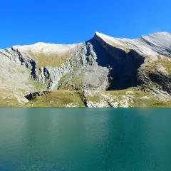 Lac d'altitude aux eaux turquoise, bordé de montagnes rocheuses et herbeuses. Un paysage qui évoque la beauté sauvage du tour du Queyras, mais aussi sa difficulté.