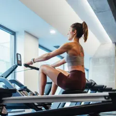 Femme concentrée sur un rameur, profitant du rameur bienfait pour un entraînement complet du corps.