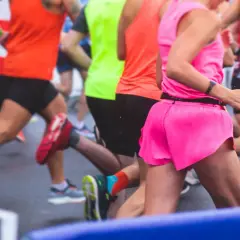 Des coureurs en tenues vives s'élancent sur la piste mouillée. L'un d'eux, en rose vif, semble vivre son premier marathon, déterminé.