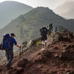Un groupe de randonneurs progresse sur un sentier rocailleux, profitant d'un paysage randonnée montagne spectaculaire.