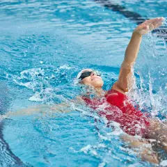 Une nageuse en action, prouvant que la natation est le sport le plus complet. L'eau éclabousse autour d'elle.