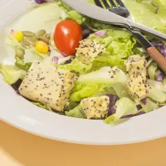 Salade fraîche avec cubes de tofu aux graines, tomate et maïs. Parfait quel petit déjeuner avant sport pour l'énergie.