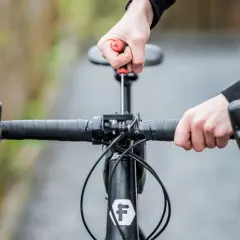 Ajustement du guidon de vélo avec un tournevis. Les mains manipulent la potence pour remonter le guidon vélo.