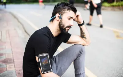Un homme avec des écouteurs sans fil et un brassard pour téléphone, profitant de courir avec musique sans téléphone.