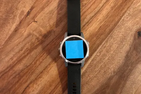 Montre connectée Garmin avec un post-it bleu sur l'écran, prête pour une aventure avec son GPS Galileo.