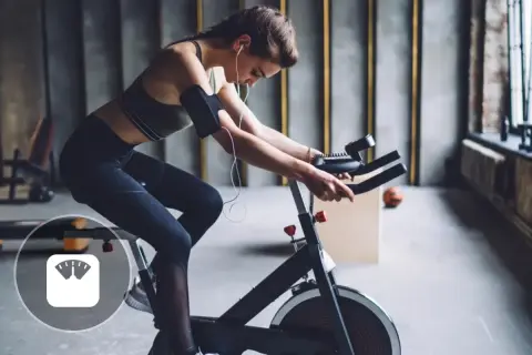 Femme en tenue de sport faisant du spinning, un sport qui aide à perdre du poids.
