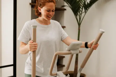 Femme souriante sur un vélo elliptique, suivant un programme vélo elliptique perdre graisse.