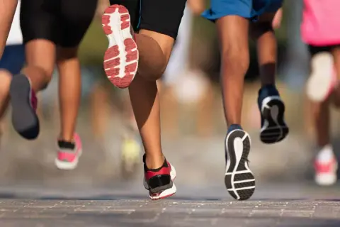 Des coureurs en action, leurs pieds chaussés de baskets dynamiques, illustrent parfaitement l'élan pour apprendre à courir.