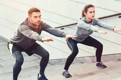 Un couple fait des squats sur des marches, un excellent exercice pour perdre du poids.