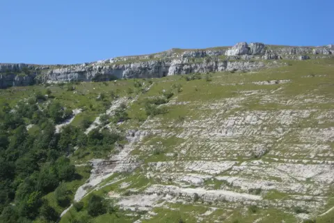 Paysage rocheux et verdoyant du Jura, idéal pour une randonnée boucle 5 jours. Le sentier serpente entre falaises et prairies.