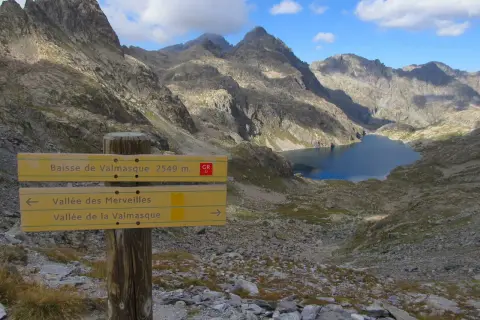 Panneau indicateur pour la randonnée vallée des Merveilles 2 jours. Lac d'altitude et montagnes escarpées.