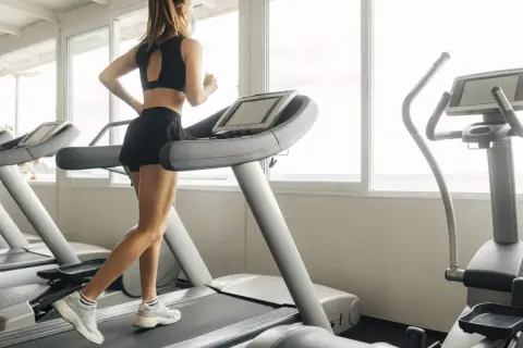 Une femme court sur un tapis de course, profitant d'une séance d'entraînement avec vue sur la mer.