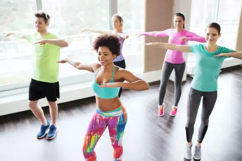 Groupe joyeux en cours de zumba pour maigrir, dansant avec énergie et sourires.
