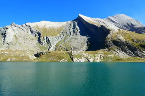 Lac d'altitude aux eaux turquoise, bordé de montagnes rocheuses et herbeuses. Un paysage qui évoque la beauté sauvage du tour du Queyras, mais aussi sa difficulté.