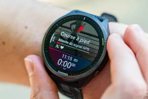 Montre Garmin affichant "Course à pied - Attente du signal GPS". Une panne Garmin Connect empêche le suivi de l'activité.