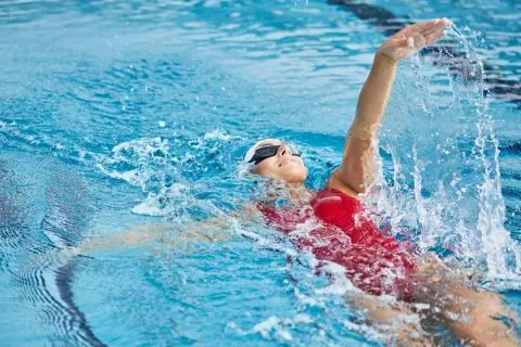 Une nageuse en action, prouvant que la natation est le sport le plus complet. L'eau éclabousse autour d'elle.