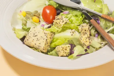 Salade fraîche avec cubes de tofu aux graines, tomate et maïs. Parfait quel petit déjeuner avant sport pour l'énergie.