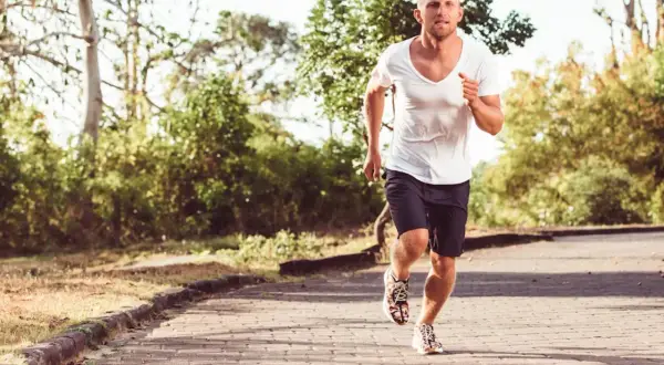 Homme courant sur un chemin pavé, le souffle court, peut-être à cause d'un vo2 max faible.