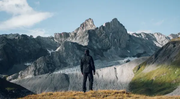Un randonneur contemple les sommets majestueux du tour des glaciers de la Vanoise 3 jours. Paysage alpin grandiose.