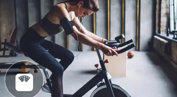 Femme en tenue de sport faisant du spinning, un sport qui aide à perdre du poids.
