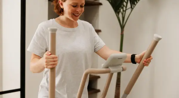 Femme souriante sur un vélo elliptique, suivant un programme vélo elliptique perdre graisse.