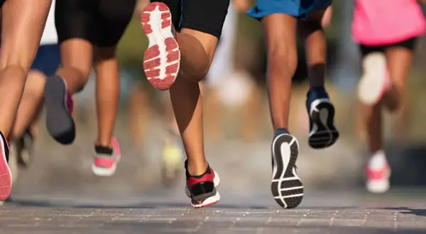 Des coureurs en action, leurs pieds chaussés de baskets dynamiques, illustrent parfaitement l'élan pour apprendre à courir.