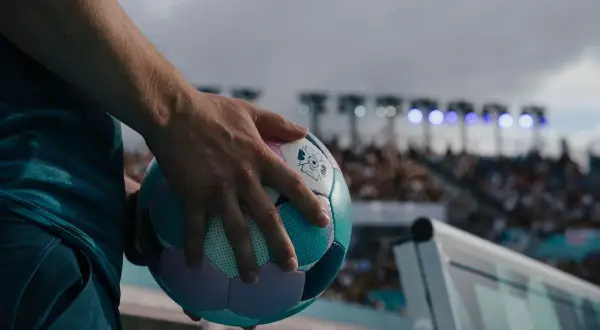 Main tenant une balle de cecifoot, prêt pour le match. Les règles du jeu sont claires, l'excitation monte dans le stade.