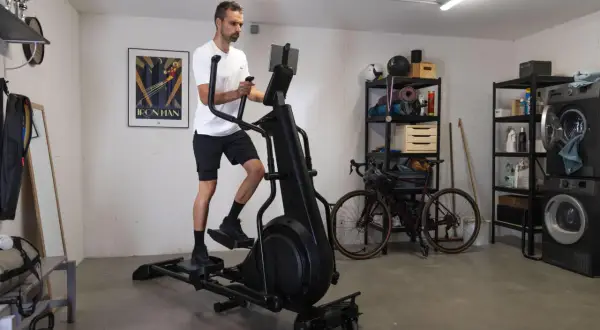 Homme s'entraînant sur un vélo elliptique pour la perte de poids dans un garage aménagé.
