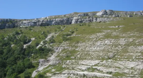 Paysage rocheux et verdoyant du Jura, idéal pour une randonnée boucle 5 jours. Le sentier serpente entre falaises et prairies.