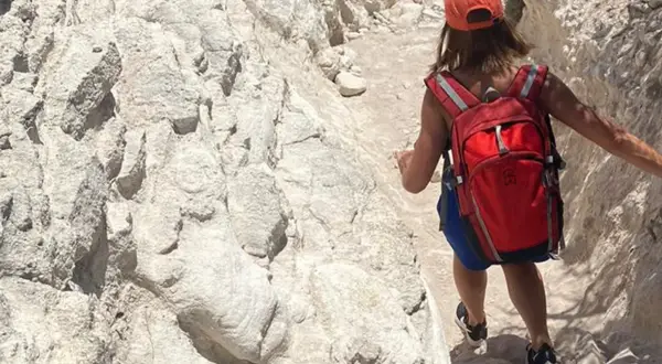 Randonneuse avec sac à dos rouge sur un sentier rocailleux, tout l'équipement nécessaire pour le GR20.