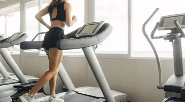 Une femme court sur un tapis de course, profitant d'une séance d'entraînement avec vue sur la mer.