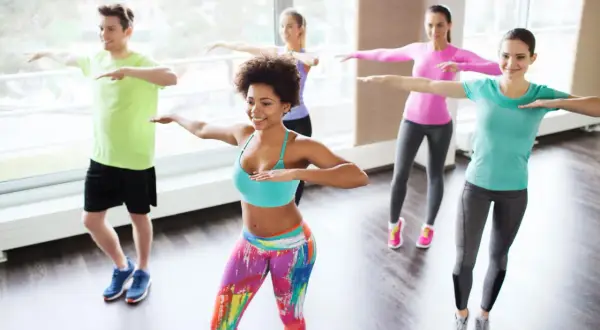 Groupe joyeux en cours de zumba pour maigrir, dansant avec énergie et sourires.