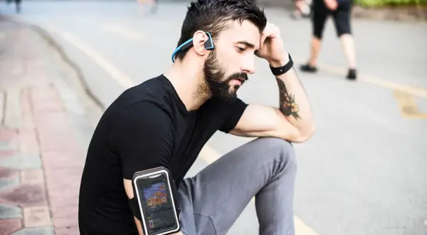 Un homme avec des écouteurs sans fil et un brassard pour téléphone, profitant de courir avec musique sans téléphone.