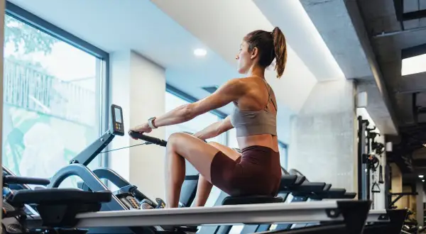 Femme concentrée sur un rameur, profitant du rameur bienfait pour un entraînement complet du corps.
