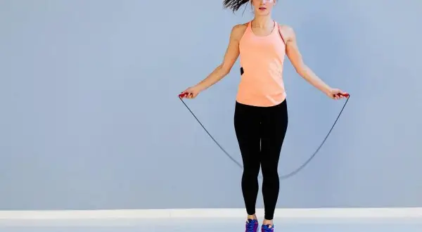 Femme en tenue de sport sautant à la corde, profitant du bienfait corde à sauter pour un entraînement cardio efficace.