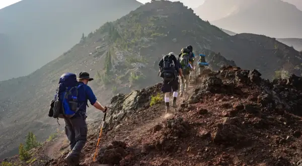 Un groupe de randonneurs progresse sur un sentier rocailleux, profitant d'un paysage randonnée montagne spectaculaire.