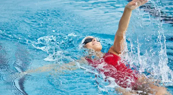 Une nageuse en action, prouvant que la natation est le sport le plus complet. L'eau éclabousse autour d'elle.
