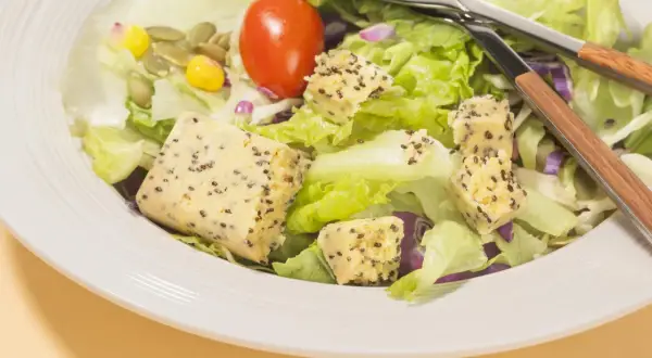 Salade fraîche avec cubes de tofu aux graines, tomate et maïs. Parfait quel petit déjeuner avant sport pour l'énergie.