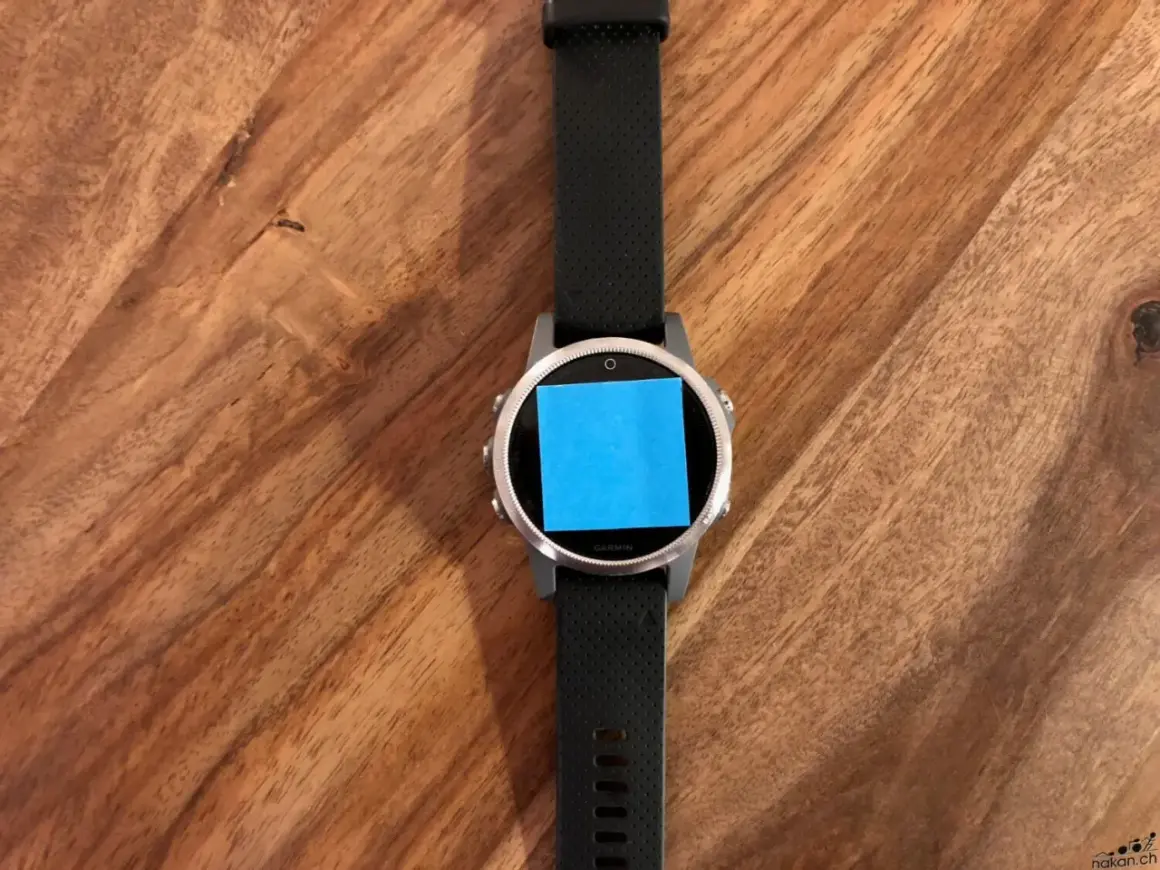Montre connectée Garmin avec un post-it bleu sur l'écran, prête pour une aventure avec son GPS Galileo.